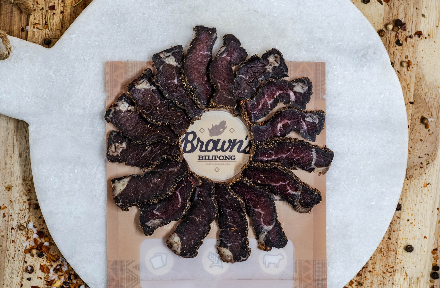 Slices of biltong are laid in a neat fanned out circle shape around the browns biltong logo.